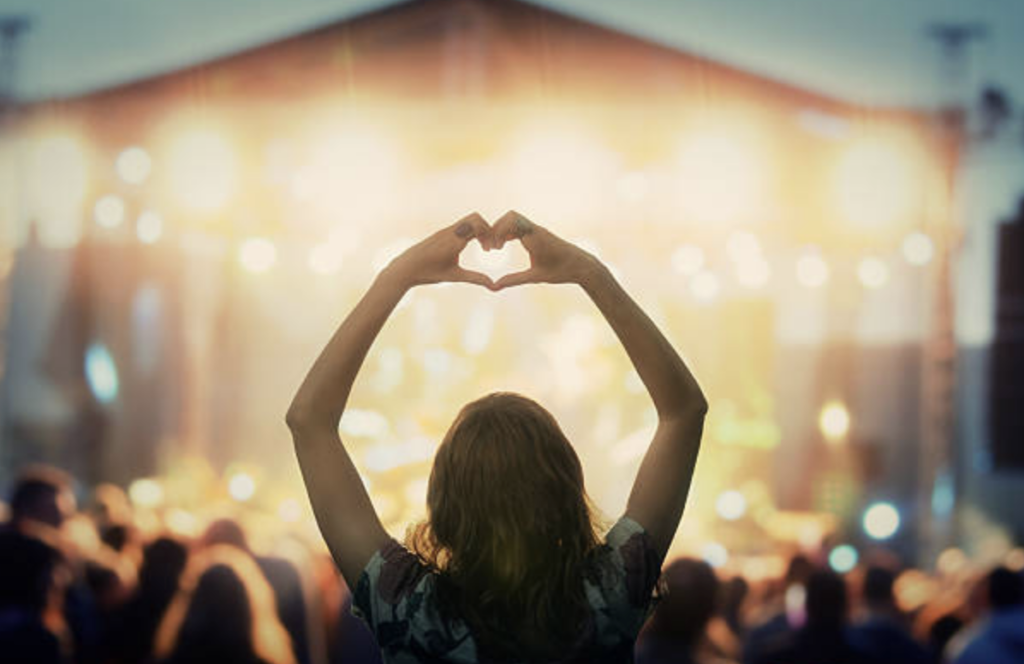 Girl making heart with hands at concert